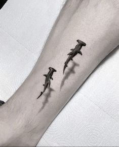 a man's arm with three shark tattoos on it