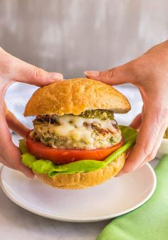 a person is holding a hamburger on a plate