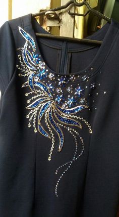 a blue dress with sequins on it hanging from a hanger in front of a door