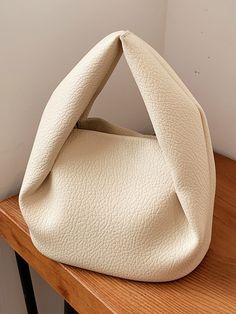 a white purse sitting on top of a wooden table