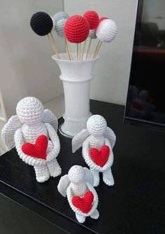 three crocheted angels with hearts in front of a vase