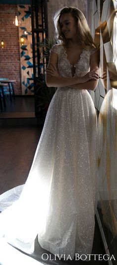 a woman standing in front of a window wearing a wedding dress