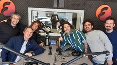 five people sitting at a table in front of microphones