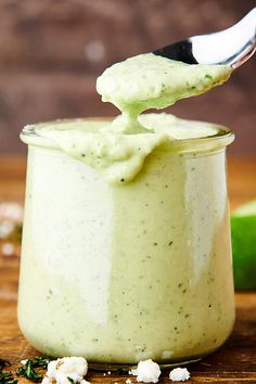 a spoon full of guacamole sauce on top of a wooden table