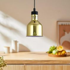 a light that is hanging from a ceiling in a kitchen with fruit on the counter