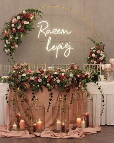 a table with candles, flowers and birdcages in front of a neon sign