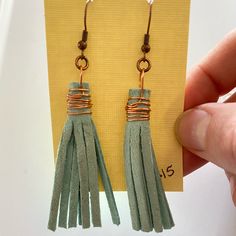 a pair of green tasselled earrings sitting on top of a card