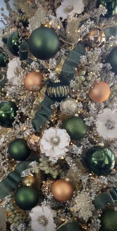 a decorated christmas tree with ornaments on it's branches and gold, green and white decorations