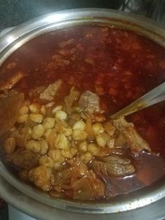 a pot filled with stew and beans on top of a stove