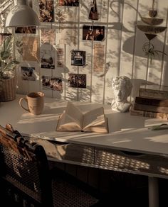 an open book sitting on top of a white table next to a vase and lamp