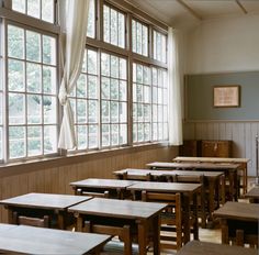 an empty classroom with wooden desks and windows