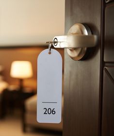 a hotel room door with a price tag hanging on it's handle and two lamps in the background