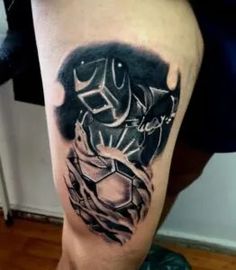 a man's leg with a black and grey tattoo design on his thigh,