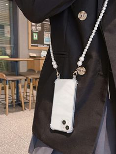 a person wearing a black jacket and holding a white cell phone case with pearls on it