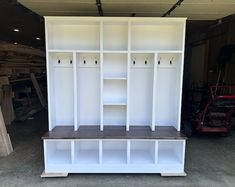 a white bookcase with shelves and benches in a garage