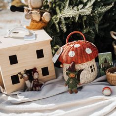 an assortment of stuffed animals and toys on a blanket next to a small wooden house