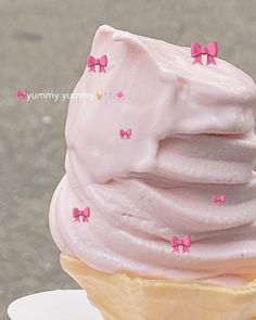 an ice cream cone with pink frosting and bows