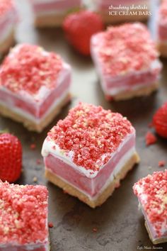 strawberry shortbreads with white frosting and sprinkles on a baking sheet