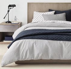 a bed with black and white striped comforter next to a night stand