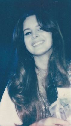 a woman with long hair smiling for the camera