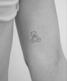 a small teddy bear tattoo on the left inner arm and leg, with an outline of a teddy bear