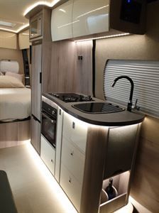 the interior of a camper with a bed, sink and stove top in it