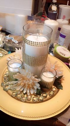 a candle and some candles on a plate with other items around the table in the background