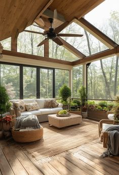 a sun room with wooden floors and large windows, furniture and potted plants on the floor