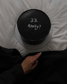 a woman is holding her cell phone in front of a black cake with the words 33 really on it