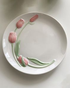 a white plate with pink flowers painted on the side and green stems in the middle