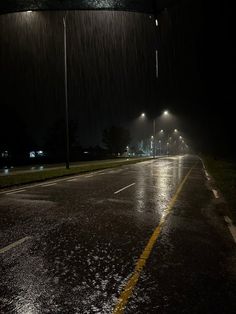 an empty street at night with the lights on and rain coming down from the sky