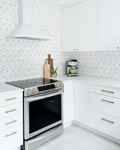 a stove top oven sitting inside of a kitchen next to white cabinets and counter tops