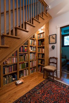 a wooden book shelf filled with lots of books next to a stair case full of books