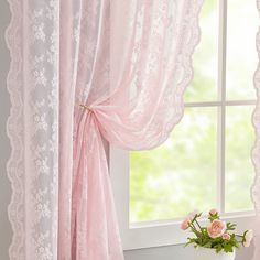 a vase with flowers in it sitting next to a window sill and pink curtains