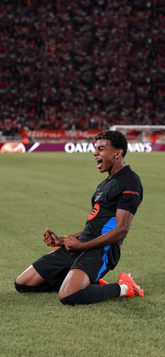 a soccer player sitting on the ground with his hands in his pockets and mouth open