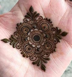 someone is holding their hand with an intricate design on it's palm, which looks like a flower ornament