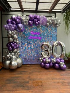 the balloon letters are purple and silver in front of a backdrop with balloons that spell out the number thirty