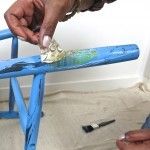 a man is painting a blue bench with paintbrushes on the floor next to him