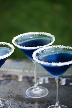 three martini glasses filled with blue liquid