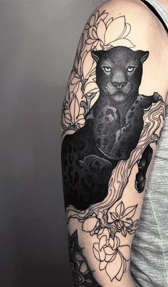 a woman's arm with a black cat and flowers tattoo on the left shoulder