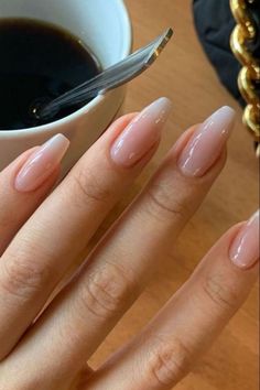 a woman's hand with french manies next to a cup of coffee