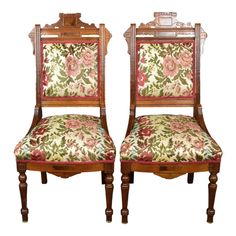 a pair of wooden chairs with floral upholstered seats