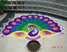 a colorful peacock design on the ground in front of a building with a potted plant