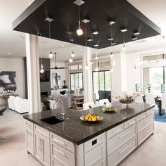 a large kitchen with an island in the middle and lots of lights hanging from the ceiling