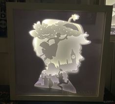 the silhouette of a child's head is projected in an illuminated shadow box on a table