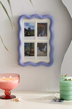 a white table topped with a pink bowl next to a wall mounted mirror and candle holder