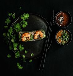 two plates with food on them and chopsticks next to one plate filled with shrimp