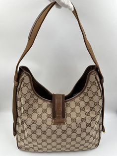 A stunning vintage Gucci Jackie tote hobo bag made from the iconic GG beige canvas with brown leather trim and gold hardware. Inside the bag is lined with brown cotton lining and there is a zipped pocket for valuables. This bag is in good vintage condition with some slight wear to the base and leather parts. Made in Italy. Height: 29cm Width: 29cm Depth: 9cm To ensure you’re completely satisfied with your purchase, please refer to the images for the exact condition of the item.