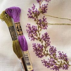 two skeins of yarn next to some purple flowers