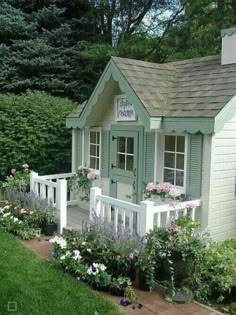 a small white house with flowers around it